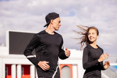 Genç, yakışıklı bir adam ve güzel bir kadın spor yaparken eğleniyorlar.