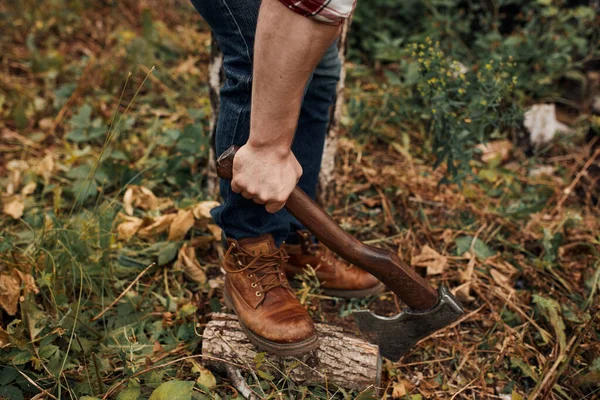 Man checkered shirt holding old axe on stump with leg — Stock Photo, Image