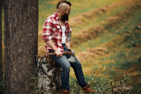 Dřevorubec sedí v lese a odpočívá po tvrdé práci — Stock fotografie