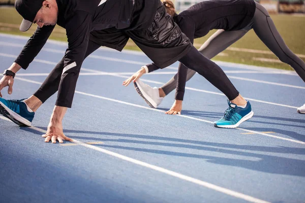 Close up cropped photo. fit people warming up their legs before the race — Stock Photo, Image