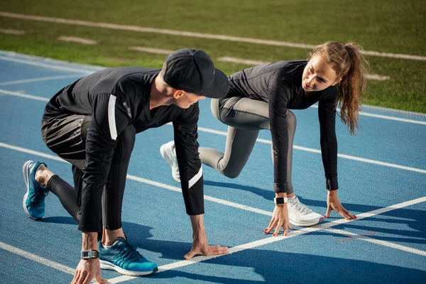 Sportsman and sportswoman looking at each other while standing on the start position — Stock Photo, Image