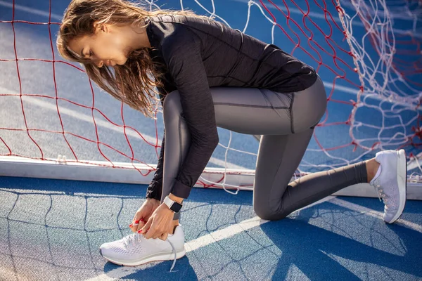 A fiatal szőke nő beköti a cipőjét a maraton előtt. — Stock Fotó