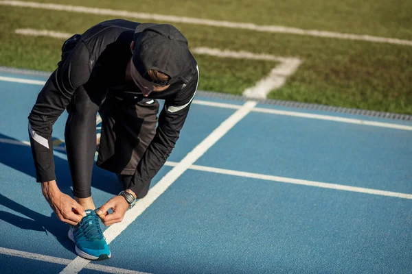 Sportsman tying shoelace during running on the road — Stock Photo, Image