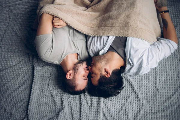 Knappe slaperige man met borstel zoenen goede nacht mannelijke partner liggend in bed — Stockfoto
