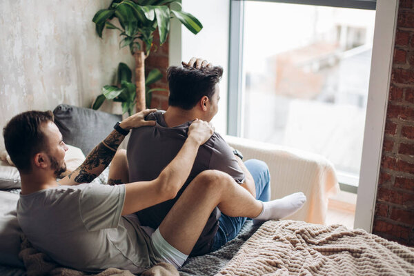 Two sexy caucasian gay guys hugging and having fun in bed indoors