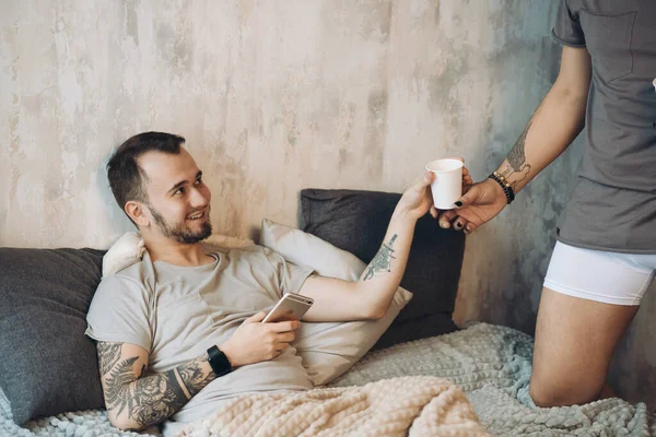 Mañana perfecta comienza con amante y café en la cama. Dos tíos descansando en la cama . — Foto de Stock