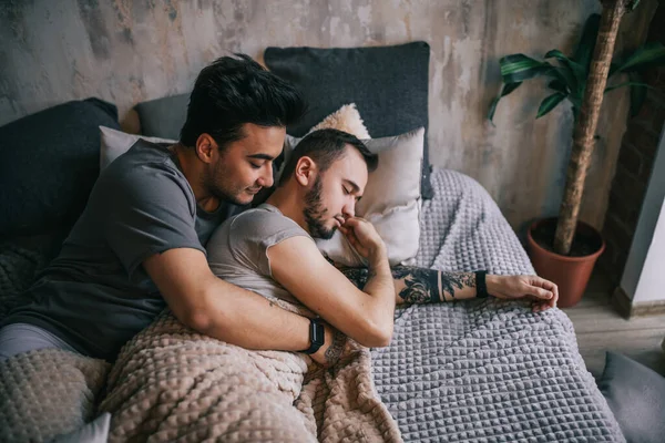 Positive delighted non-traditional couple sleeping together