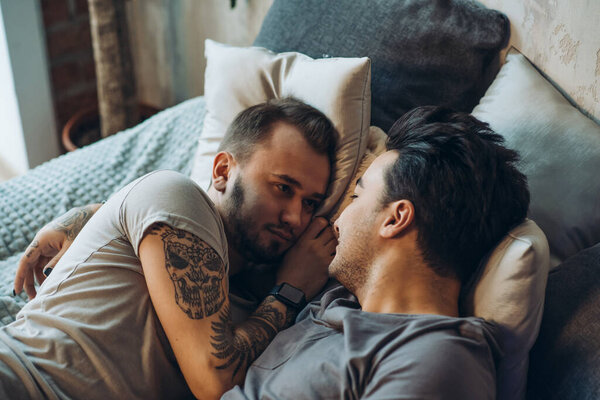 A homosexual couple on bed in studio with loft interior