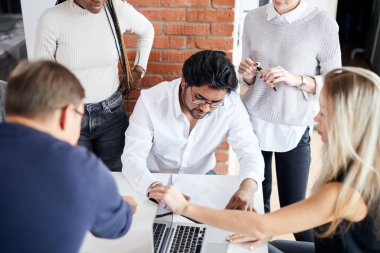 Hindu adam belgelerle uğraşırken diğerleri onu kontrol ediyor.