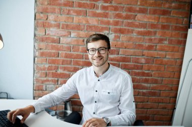 pozitif traşsız ofis çalışanı kameraya bakıyor.