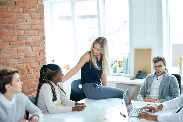 Rubia chica es sentado en el borde de la mesa y hablando con afro mujer mientras romper — Foto de Stock