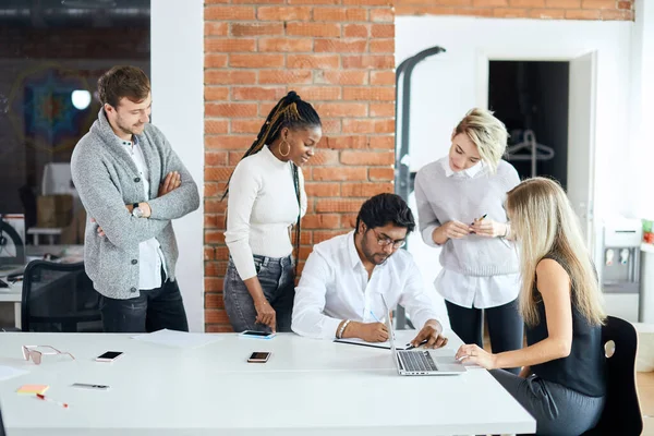 Líder de la empresa firmando los documentos mientras sus colegas lo miran — Foto de Stock