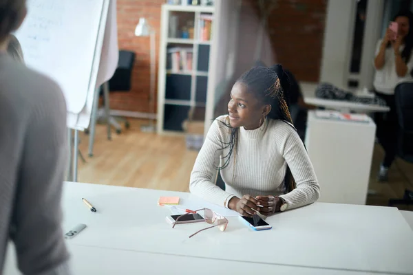 Empresaria sentada a la mesa y escuchando la oferta de los clientes — Foto de Stock