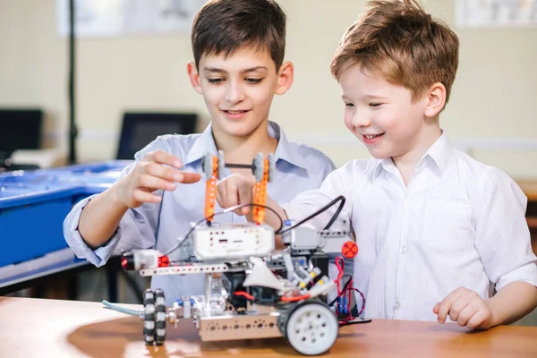 Dua bersaudara bermain dengan mainan robot di kelas robotika sekolah, di dalam ruangan. — Stok Foto