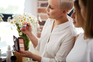 Profesyonel öğretmen, öğrencilerine makyaj eğitimi veriyor.