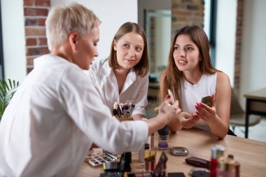 Profesyonel öğretmen, öğrencilerine makyaj eğitimi veriyor.