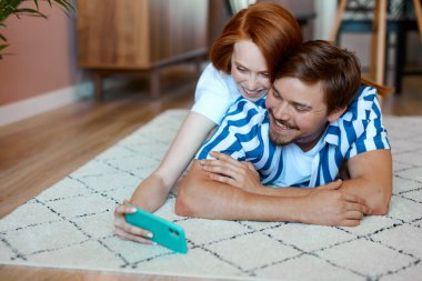 Çift evde akıllı telefon kullanarak fotoğraf çekiyor.