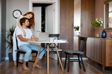 Kadın çalışan kocasına masaj yapıyor.