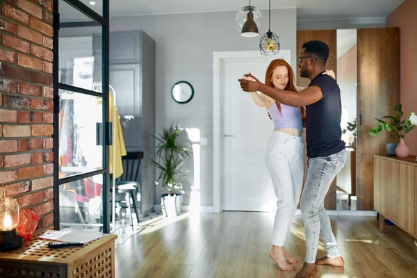 lovely young multiethnic couple dance in living room