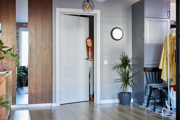 Frau guckt aus der Tür, überprüft die Wohnung — Stockfoto