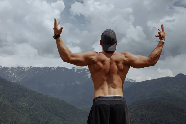 Culturista posando en las montañas. Hombre fuerte guapo mostrando sus músculos. — Foto de Stock