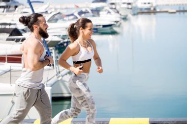 Günbatımında ahşap iskelede koşan genç bir çift.