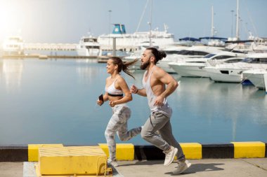 Günbatımında ahşap iskelede koşan genç bir çift.