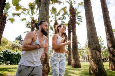 Yaz sabahı parkta koşan genç bir çift.