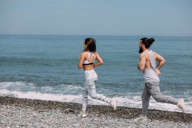 Kumsalda suyun yanında koşan mutlu çift.