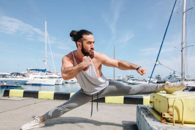 Spor yaşam tarzı. Deniz kıyısında esneyen Kafkasyalı genç ve mutlu bir vücutçu..