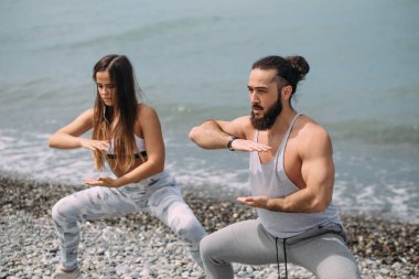 Dışarıda ısınan çiftler, birlikte çömelme hareketleri yapıyorlar.