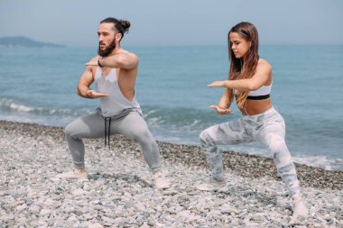 Dışarıda ısınan çiftler, birlikte çömelme hareketleri yapıyorlar.