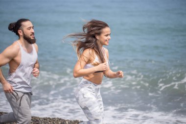 Kumsalda suyun yanında koşan mutlu çift.