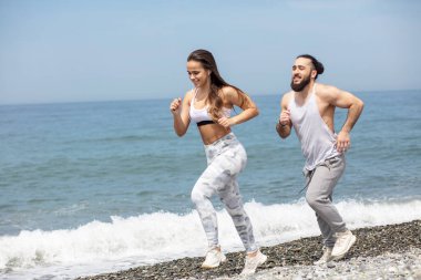 Kumsalda suyun yanında koşan mutlu çift.