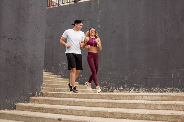 Couple running on stairs in morning, jogging in urban area with starecases.