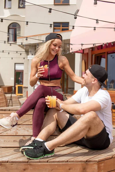 Casal esportivo sentado em um café desfrutando de bebidas frescas após o treino intensivo . — Fotografia de Stock