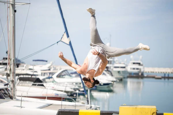 Fitness athlete doing jump squats on makeshift plyo-box on summer sea pier