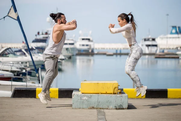 Kadın ve erkek sporcu açık havada atlama yapıyor..