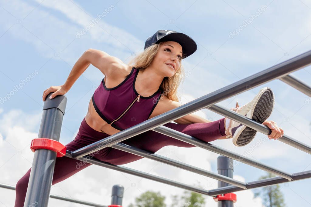 Athletic woman doing single leg split squat exercise with park equipment outdoors high buildings in background