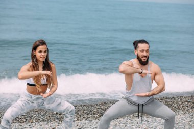 Dışarıda ısınan çiftler, birlikte çömelme hareketleri yapıyorlar.