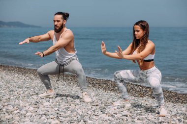 Dışarıda ısınan çiftler, birlikte çömelme hareketleri yapıyorlar.