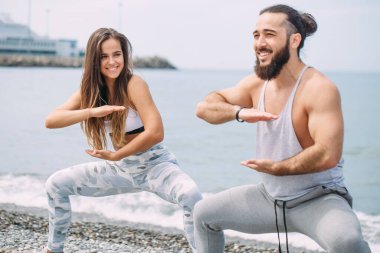 Dışarıda ısınan çiftler, birlikte çömelme hareketleri yapıyorlar.