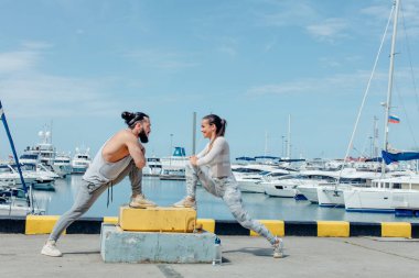 Genç ve güzel bir çift okyanus rıhtımında esneme egzersizleri yapıyor.