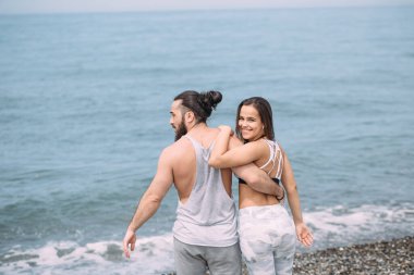 Genç fitness çifti sahilde durup ufka bakıyor.