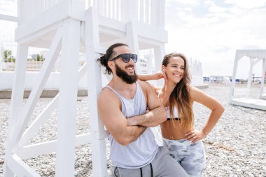 Genç çift, çakıl taşlı plajda dinlenirken kulaklıkla müzik dinliyor.