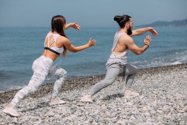 Dışarıda ısınan çiftler, birlikte çömelme hareketleri yapıyorlar.