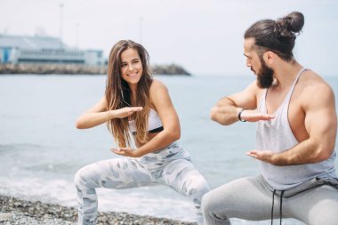 Dışarıda ısınan çiftler, birlikte çömelme hareketleri yapıyorlar.