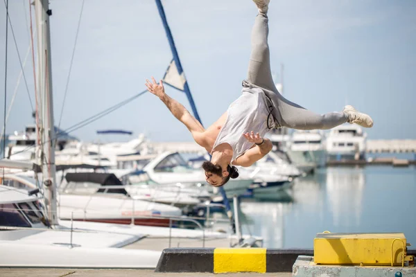 Fitness athlete doing jump squats on makeshift plyo-box on summer sea pier