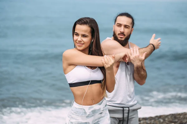 Couple stretching on beach — Stock Photo, Image