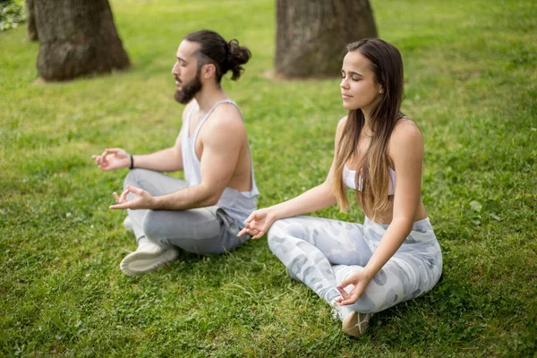 Jeune couple faisant du yoga en plein air — Photo
